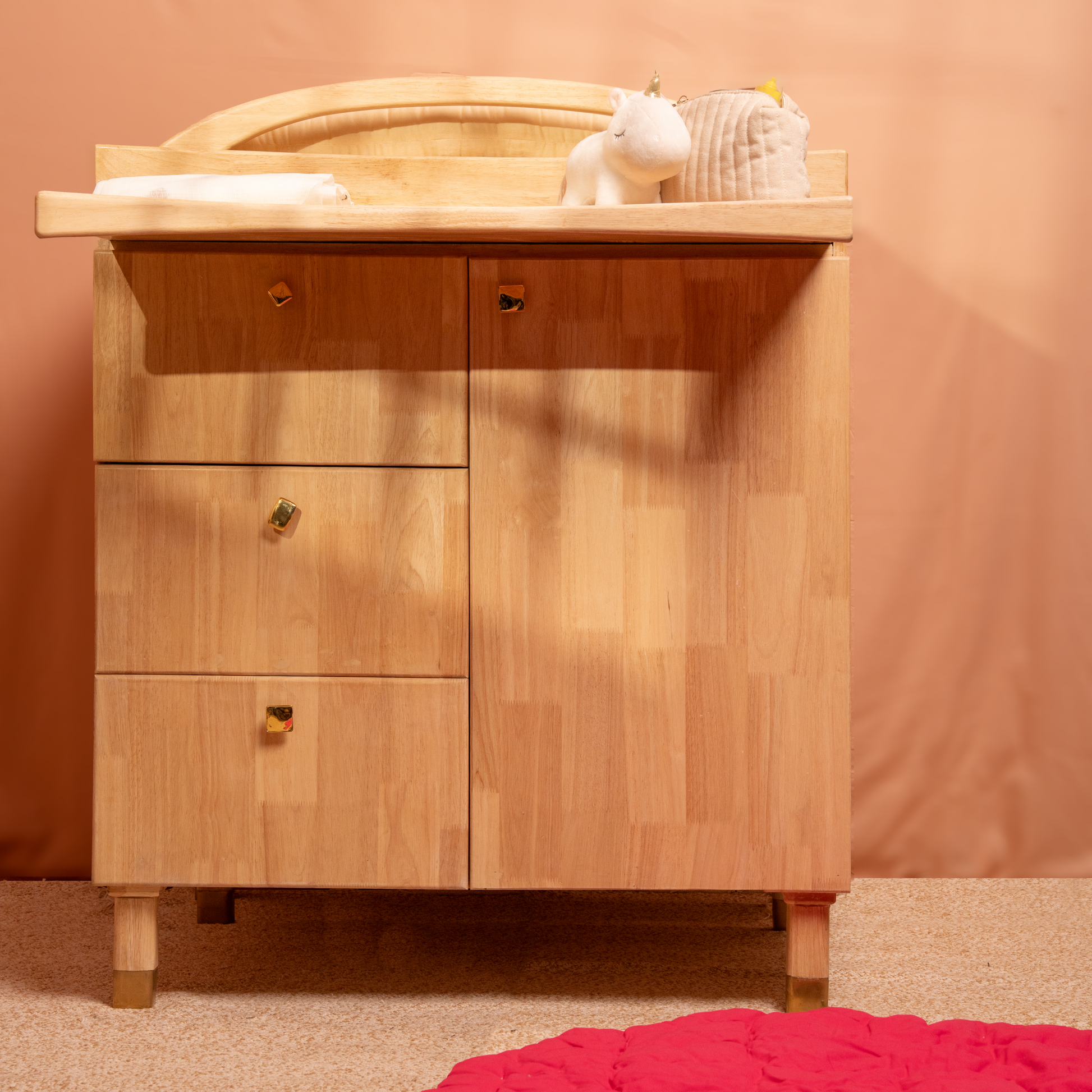 Wooden changing table with baby items with brass shiny knobs against 